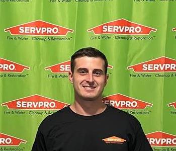 SERVPRO employee in front of green wall