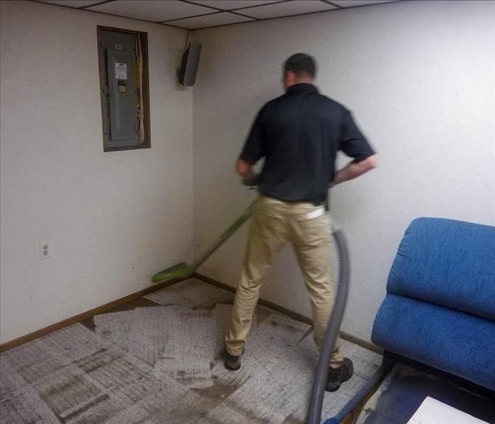 Employee vacuuming debris from room. 